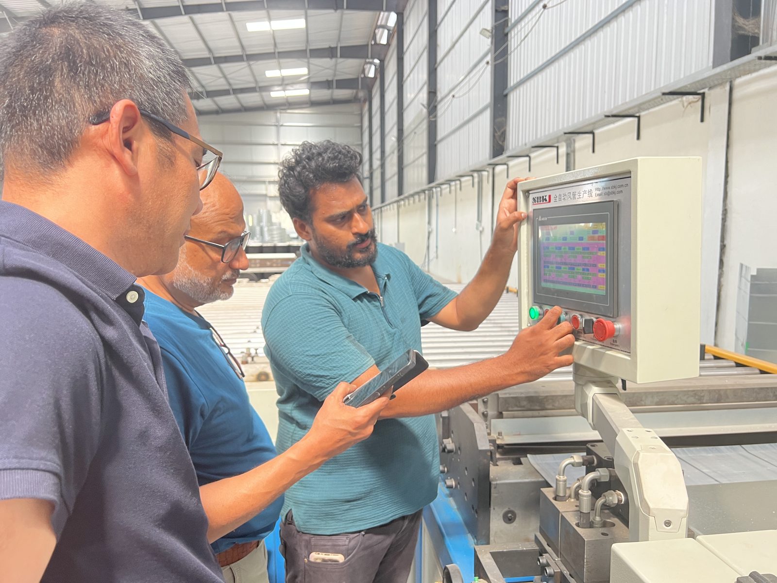 Operator training on an auto duct line control panel at an Indian duct shop
